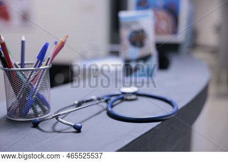 Medical Equipment On Front Desk Top With Pens And Information Leaflets In Hospital Reception. Stetho
