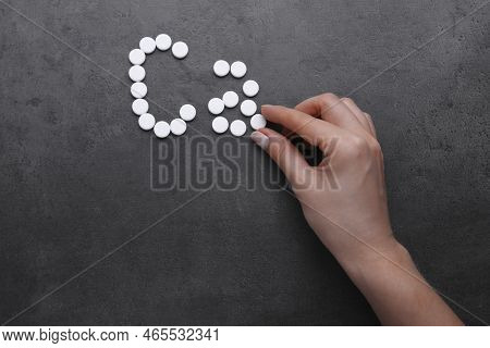 Woman Making Symbol Ca (calcium) Of Pills On Black Background, Top View