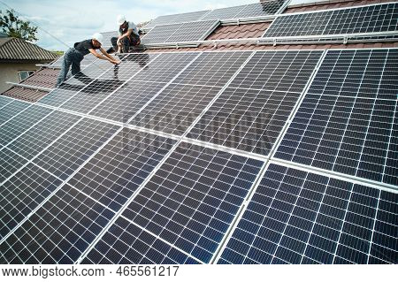 Man Technician Mounting Photovoltaic Solar Moduls On Roof Of House. Mounter In Helmet Installing Sol