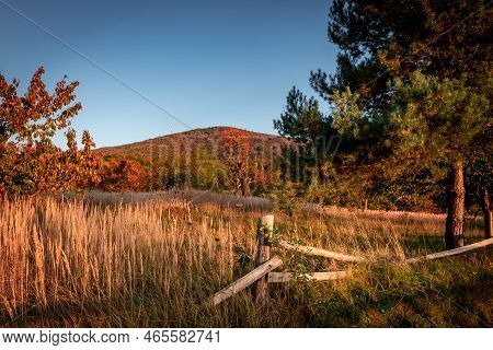 Autumnal Sunset Landscape With Sleza Mountain, Poland. Old Broken Wooden Fence In Foreground.