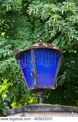 A Lantern With Blue Discson A Gatepost.