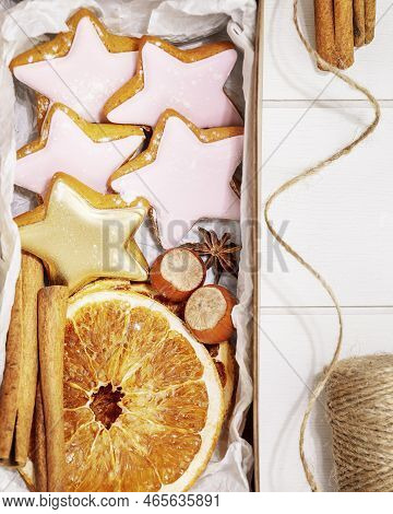 Hande Made Present With Home Made Cookies, Dry Fruits, Nuts And Cinnamon Stiks On A White Wooden Bac