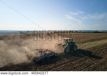 Aerial View Of Tractor Plowing Agriculural Farm Field Preparing Soil For Seeding In Summer.