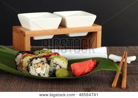 Velsmagende Maki sushi - Roll på grønne blade på bordet på grå baggrund