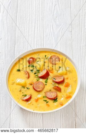 Kartoffelsuppe, German Potato Soup With Sausages In White Bowl On White Wooden Table, Vertical View 