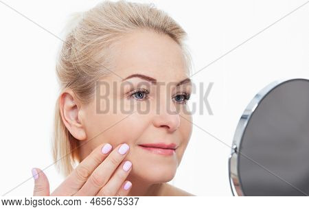 Happy Middle Aged Woman Model Touching Face Skin Looking In Mirror. Smiling Mature Older Lady Enjoyi