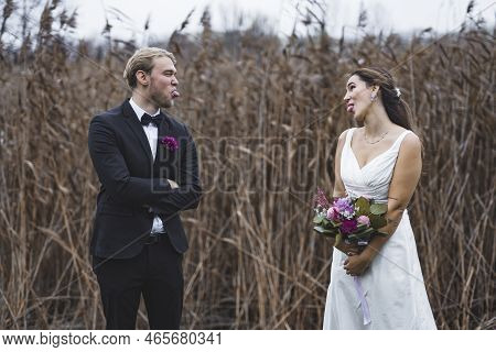 Funny Wedding Memories. Middle Eastern Bride In Beautiful White Dress And Her Caucasian Husband In T