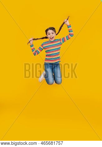 Childhood Studio Shot Of Jumping Teen Braided Girl. Teen Braided Girl Isolated On Yellow Background.