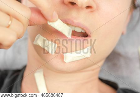 A Woman Puts A Packet Of Swedish Snus Into Her Mouth. Swedish Snus