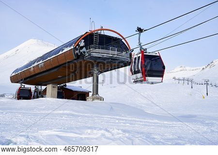 Cable Car Gondola At Ski Resort With Snowy Mountains On Background. Modern Ski Lift With Funitels An