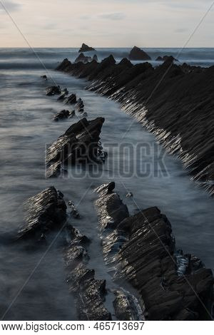 Stunning Sunset Landscape Image Of Welcome Mouth Beach In Devon England With Beautiful Rock Formatio