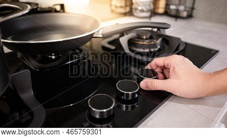 Male Hand Turning Switch Knob On Modern Gas Stove In Kitchen Showroom. Cooking Appliance In Domestic