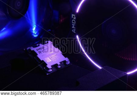 Close-up Of An Amd Ryzen 9 3900X Processor, Against The Backdrop Of Coolers With Light.