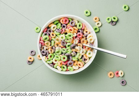 Colorful Corn Rings In Bowl On Green Background. Ring-shaped Sweet Breakfast Cereal With Milk.