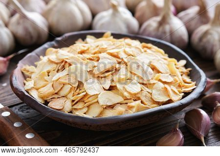 Bowl Of Dried Garlic Flakes, Garlic Cloves. Heads Of Garlic On Background. Dried Seasoning.