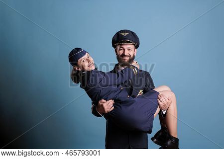 Smiling Pilot Holding Flight Attendant In Arms Portrait, Aircrew In Professional Uniform Looking At 