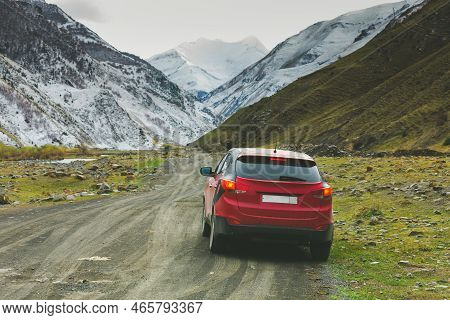 Red Car On A Dirt Road In The Mountains. Panoramic View Of The Dirt Road Among The Mountains Of Dage