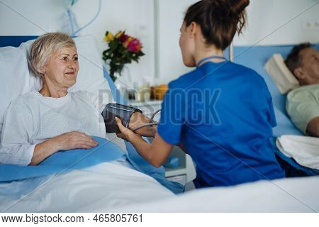 Young Nurse Chcecking Blood Presure To Senior Patient.