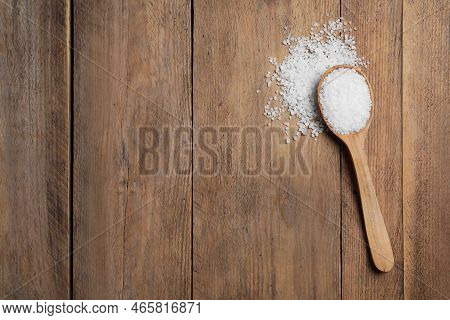 Spoon And Heap Of Natural Sea Salt On Wooden Table, Top View. Space For Text