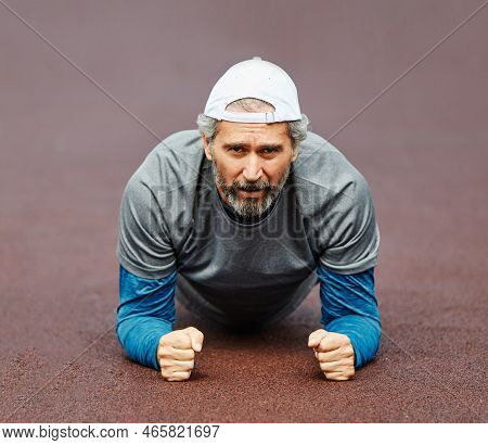Active Senior Man Stretching And Exercising Outoors In The Park
