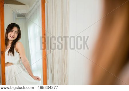 Happy Woman Wearing Dress On Front Mirror Looking Clothes At Home After Morning Wake Up, Asian Beaut