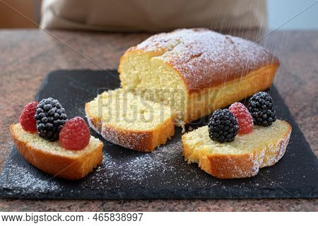 Close-up On The Homemade Plumcake Resting On A Black Stone Cutting Board While Being Dusted With Ici