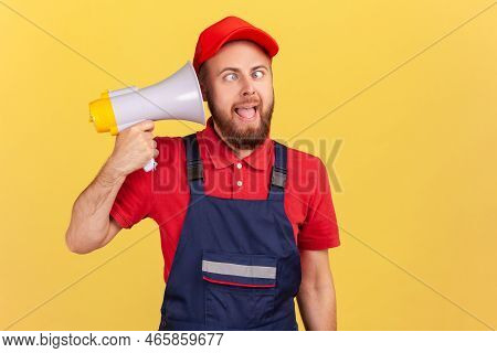 Portrait Of Funny Crazy Childish Worker Man Holding Megaphone Near Head, Frowning Face, Looking At C