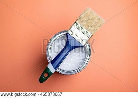 Paint Can On Which Lies A Brush With A Blue Handle On An Orange Background