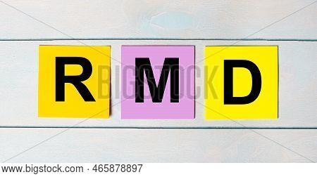 Three Multi-colored Paper Stickers With Rmd Required Minimum Distributions Text On A Blue Wooden Bac