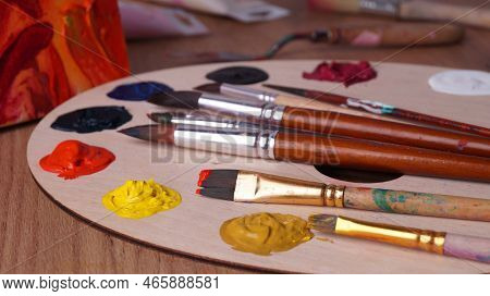 Artist's Palette With Many Colorful Paints And Brushes On Wooden Table, Closeup