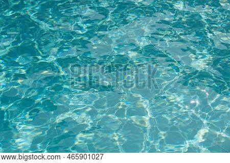 Ripple Water In Swimming Pool With Sun Reflection. Wavy Water Background.