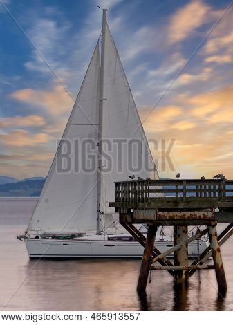 Sailboat Sails Past The Fishing Pier During Sunrise In Sidney Bc