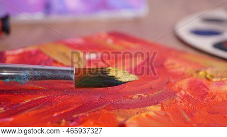 Artist's Canvas With Mixed Paints And Brush On Table, Closeup