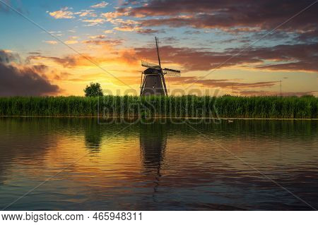 Colorful Sunset Over An Old Dutch Windmill By A River In Kinderdijk, Netherlands. This System Of 19 
