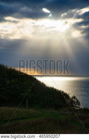 On The Coast Of Hundested. Sun Rays Breaking Through The Dramatic Sky Through The Clouds At Sunset. 