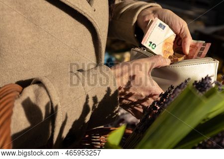 A Woman Opened Her Wallet And Pays For Purchases At An Open Food Market, Austria, Salzburg
