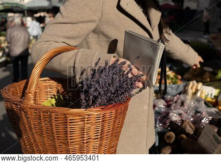A Woman Holds A Purse And A Basket Of Lavender In Her Hands And Points To The Product She Wants To B