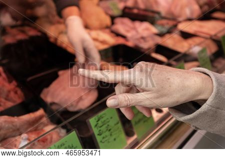 A Woman Points To An Item In A Butchers Shop That She Wants To Buy. Shopping Market, Austria, Salzbu