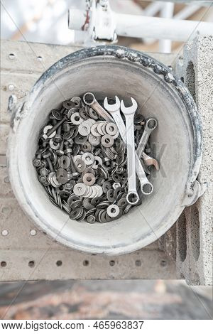 A Bucket Full Of Wrenches, Washers And Stud Bolts Is Placed On The Scaffolding.