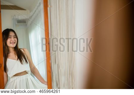 Asian Beautiful Young Woman Trying On Blouse And Smiling While Standing In Front Of Mirror In Room, 