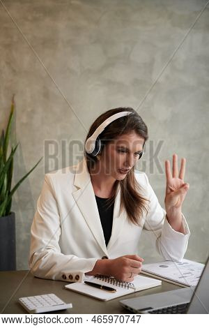 Young Elegant Businesswoman Showing Three Fingers When Talking To Colleague In Online Meeting