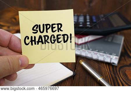 Business Concept. In The Hands Of A Man Is A Sticker With The Inscription - Super Charged. In The Ba