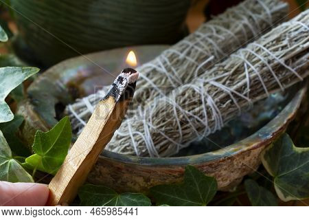 A Close Up Image Of A Burning Smudge Stick With Two White Sage Smudge Sticks In The Background.