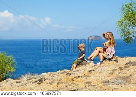 Happy Mother With Kids Walking On Summer Sea Beach Holiday. Beautiful Family Relaxing On High Ocean 