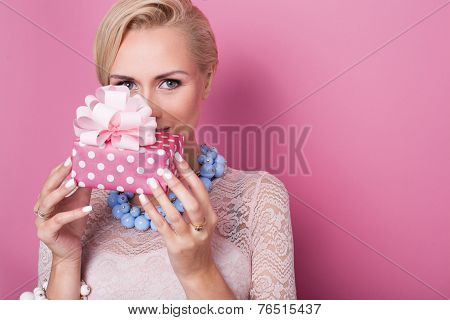 Merry christmas. Beautiful blonde woman holding small gift box with ribbon. Soft colors