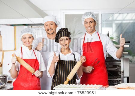 Portrait of confident chef team gesturing thumbsup together in commercial kitchen