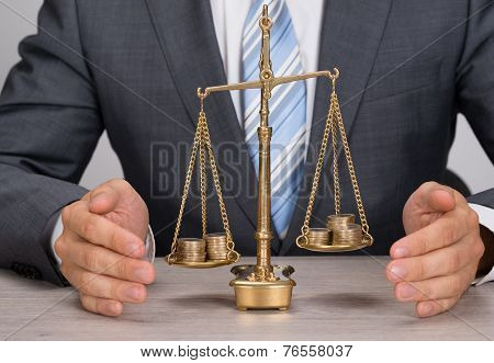 Businessman Protecting Justice Scale With Coins
