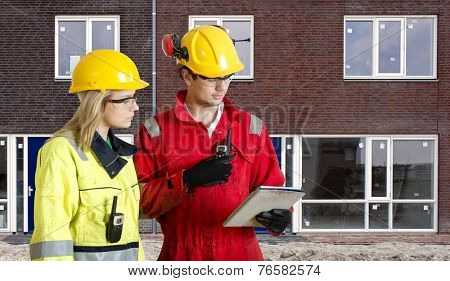 Foreman and real estate development manager going over an electronic checklist during the delivery and completion of a new housing development, constructed from prefab elements