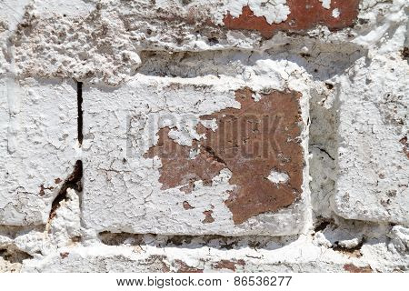 A white painted brick wall where the paint is peeling off