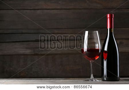 Wine bottle with glass on wooden background